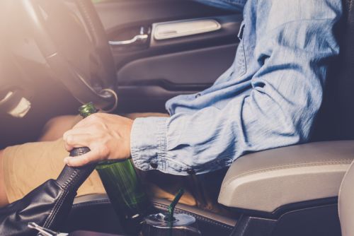 Drinking and driving ,man drinking alcohol and using mobile phone while driving car ,concept drive safely while using a cell phone or drunk alcohol concept.