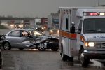 Car crash on major highway during rainfall at night. Ambulance in foreground and police car in background concept.t