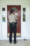officer posting a notice on a front door